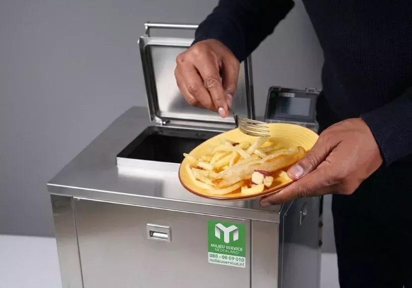 Medewerker veegt bord met etenresten in een open biovergister