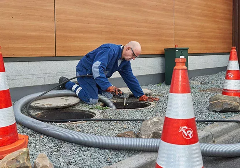 medewerker leegt buiten een vetput
