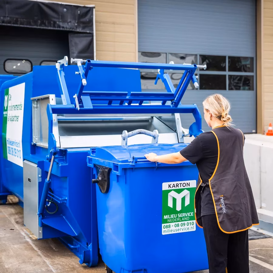 schoonmaker leegt rolcontainer papier in perscontainer