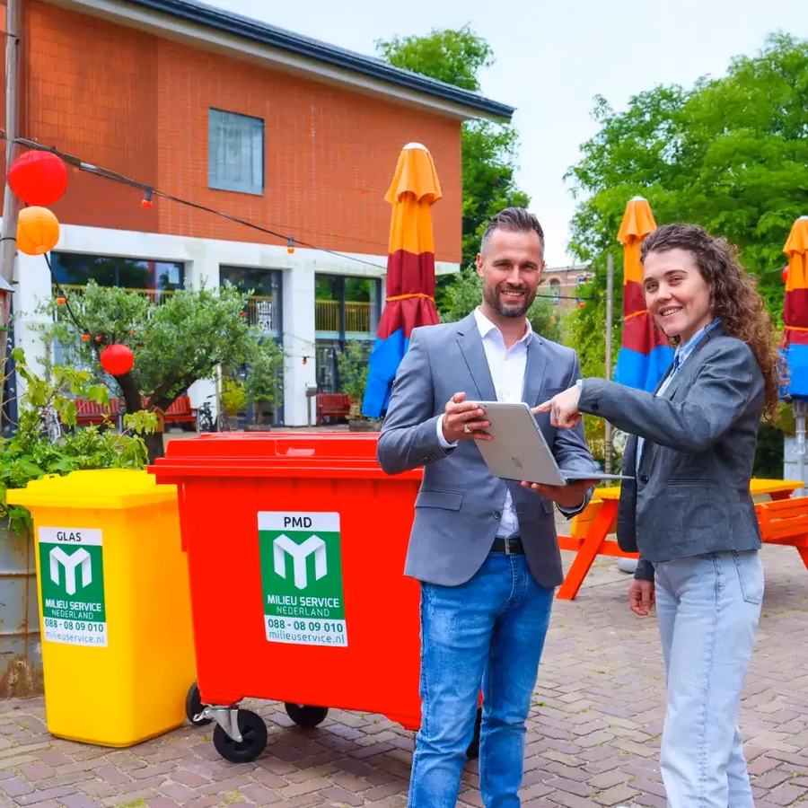 Accountmanager en klant voor een rolcontainer, kijkend naar rapportages op een scherm