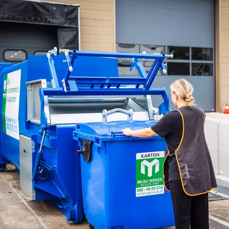 schoonmaker leegt rolcontainer papier in perscontainer