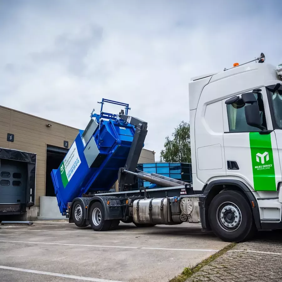 Vrachtwagen zet een papier karton perscontainer neer