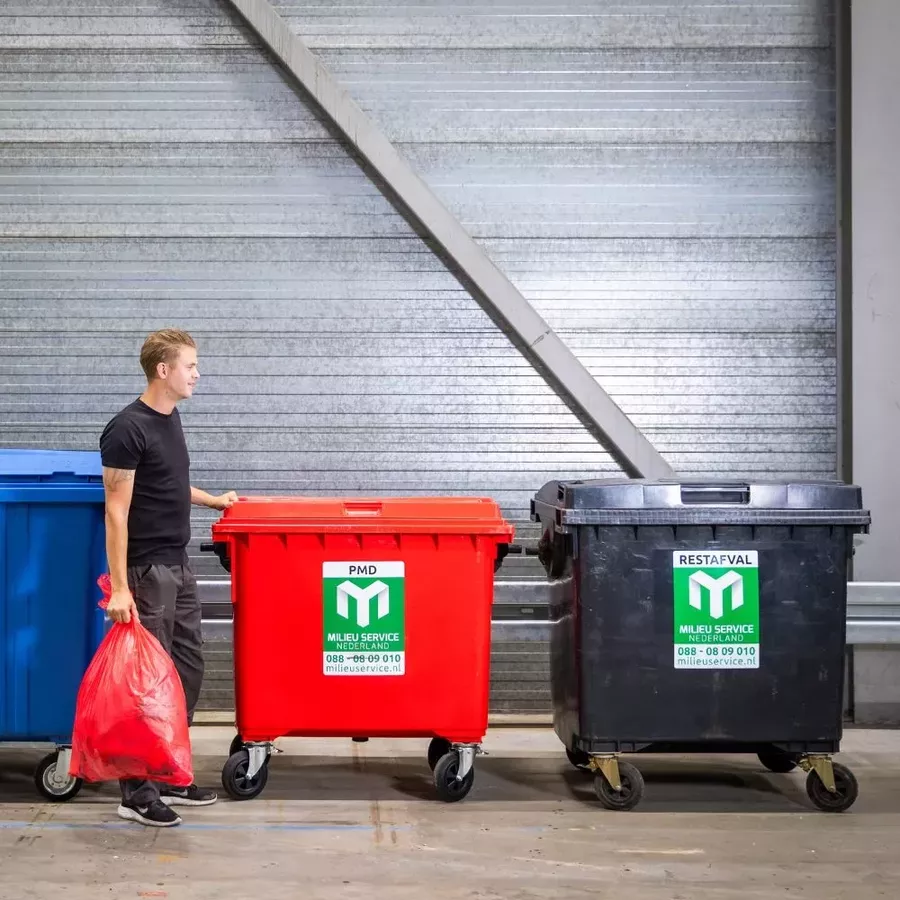 Foto van een restafval en PMD container met een persoon er linksvoor die afval weggooid.