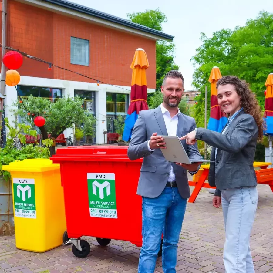 Accountmanager en klant voor een rolcontainer, kijkend naar rapportages op een scherm